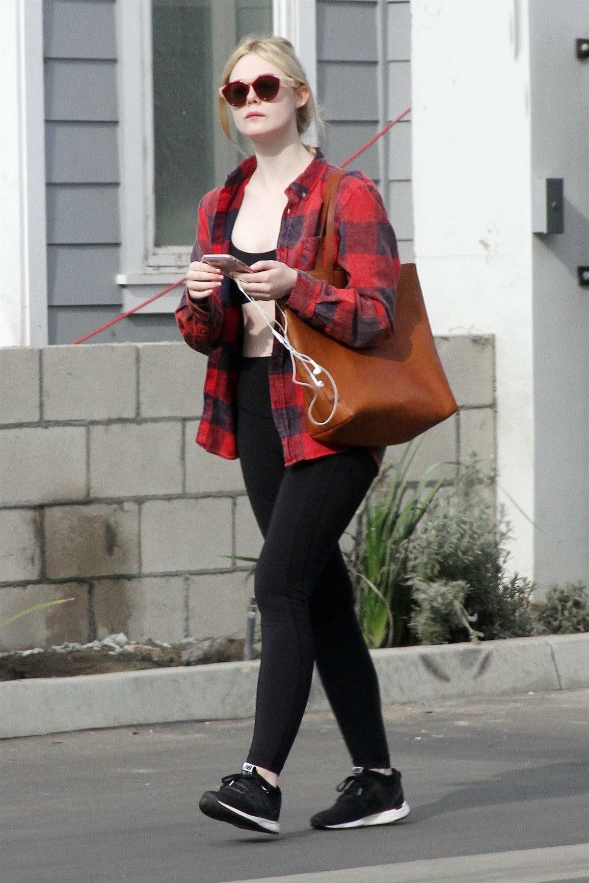 elle fanning wore red flannel shirt over a black sports bra with black leggings as she heads out 