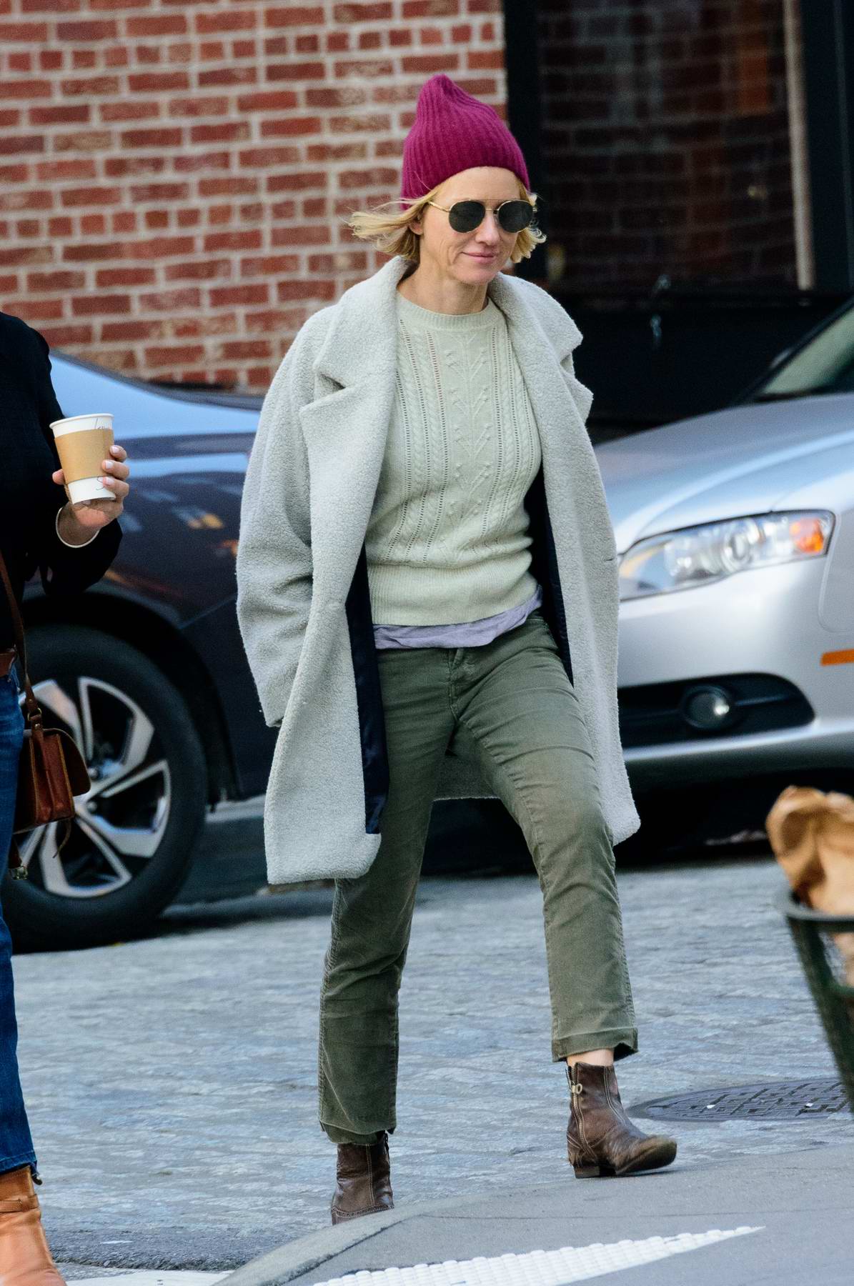 Naomi Watts wears a cable knit sweater, light grey pea coat and purple ...