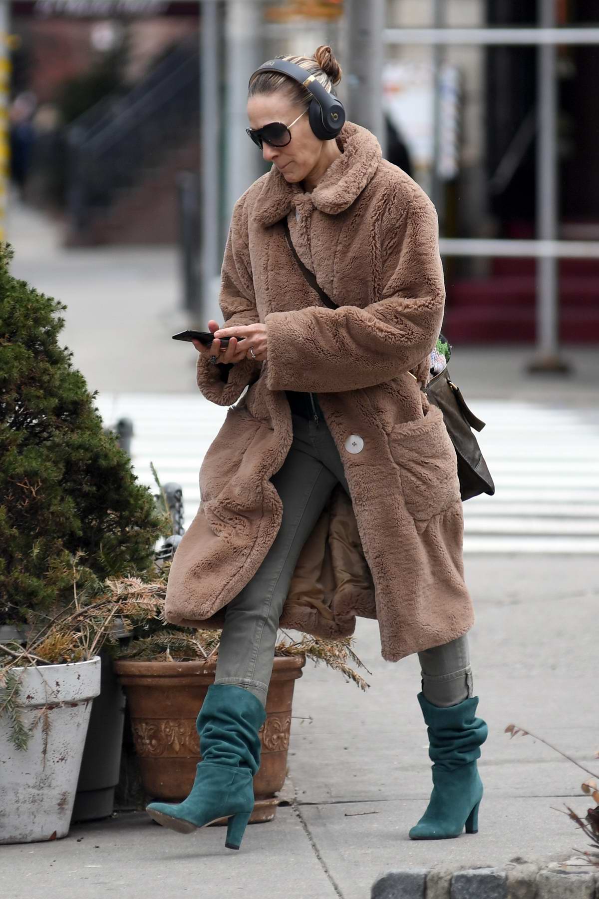 sarah jessica parker wearing headphones and a cozy brown coat