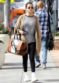 Selena Gomez wears a tan knit cardigan over a striped top and a pair of black leggings as she grabs a late breakfast in Hollywood, Los Angeles