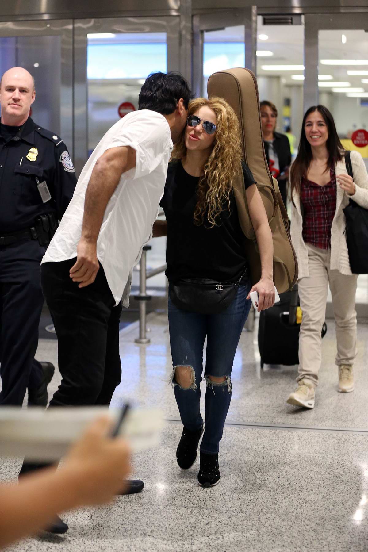 shakira rocks ripped blue jeans, black top and a guitar on her back as ...