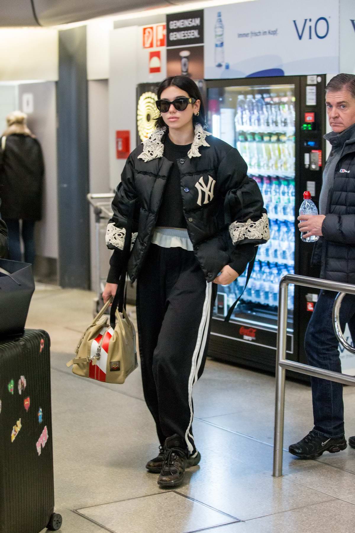 dua lipa rocks a lace-trimmed puffer jacket, track pants and louis vuitton  sneakers as she arrives at the tegel airport in berlin, germany-151118_4