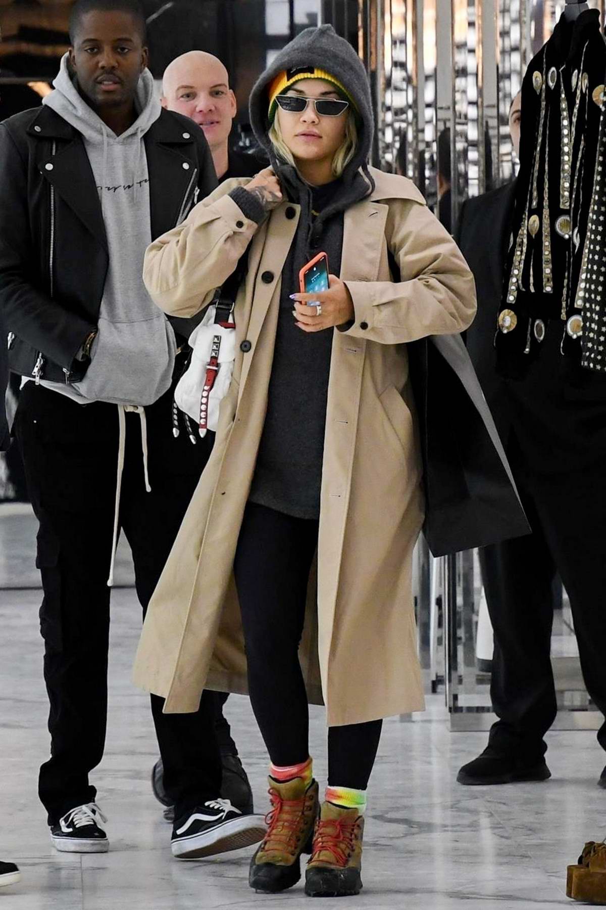 Rita Ora bundles up in a beige trench coat and colorful beanie