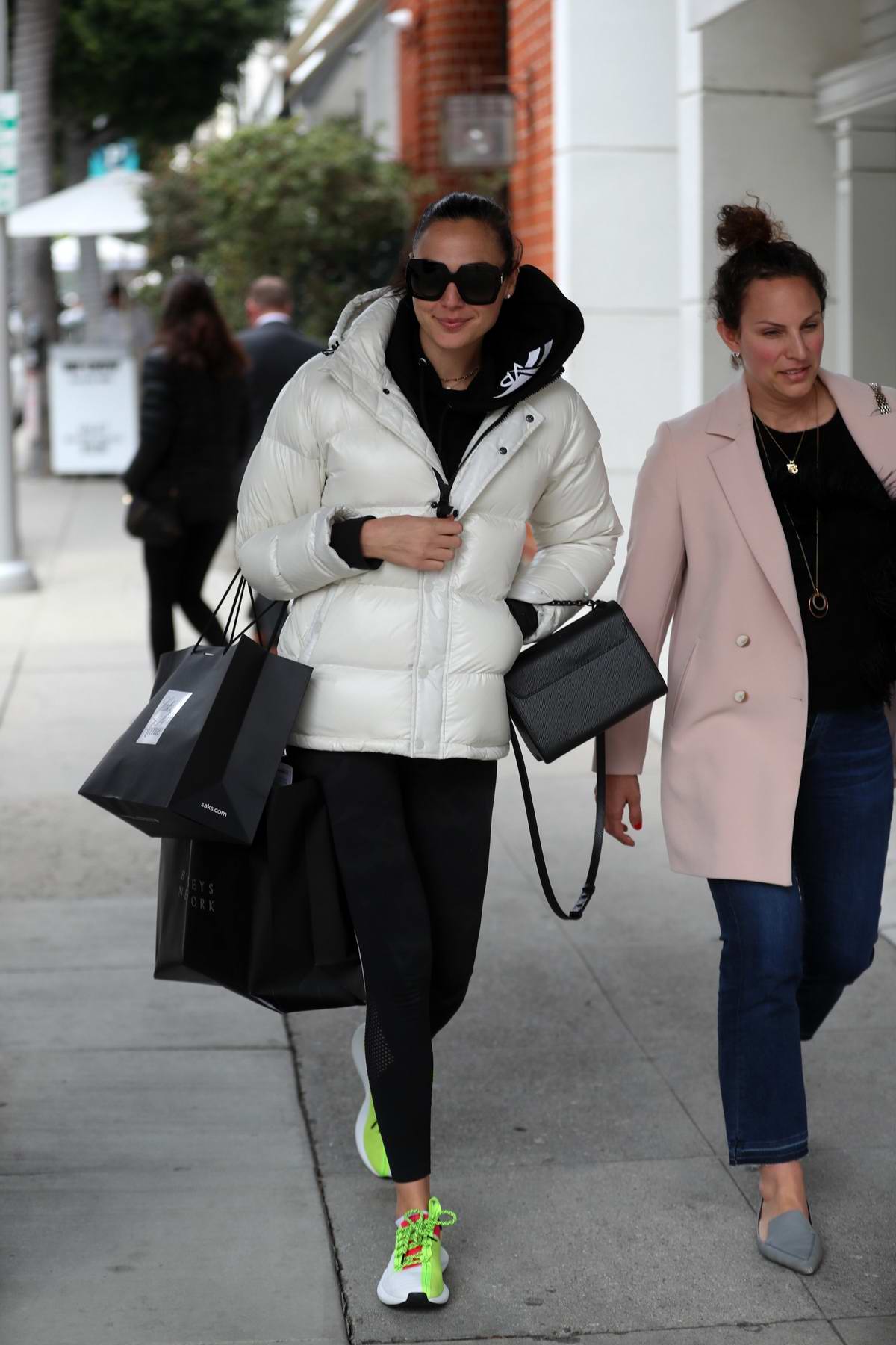 gal gadot wears a white puffer jacket and black leggings while out shopping at saks and barneys ...