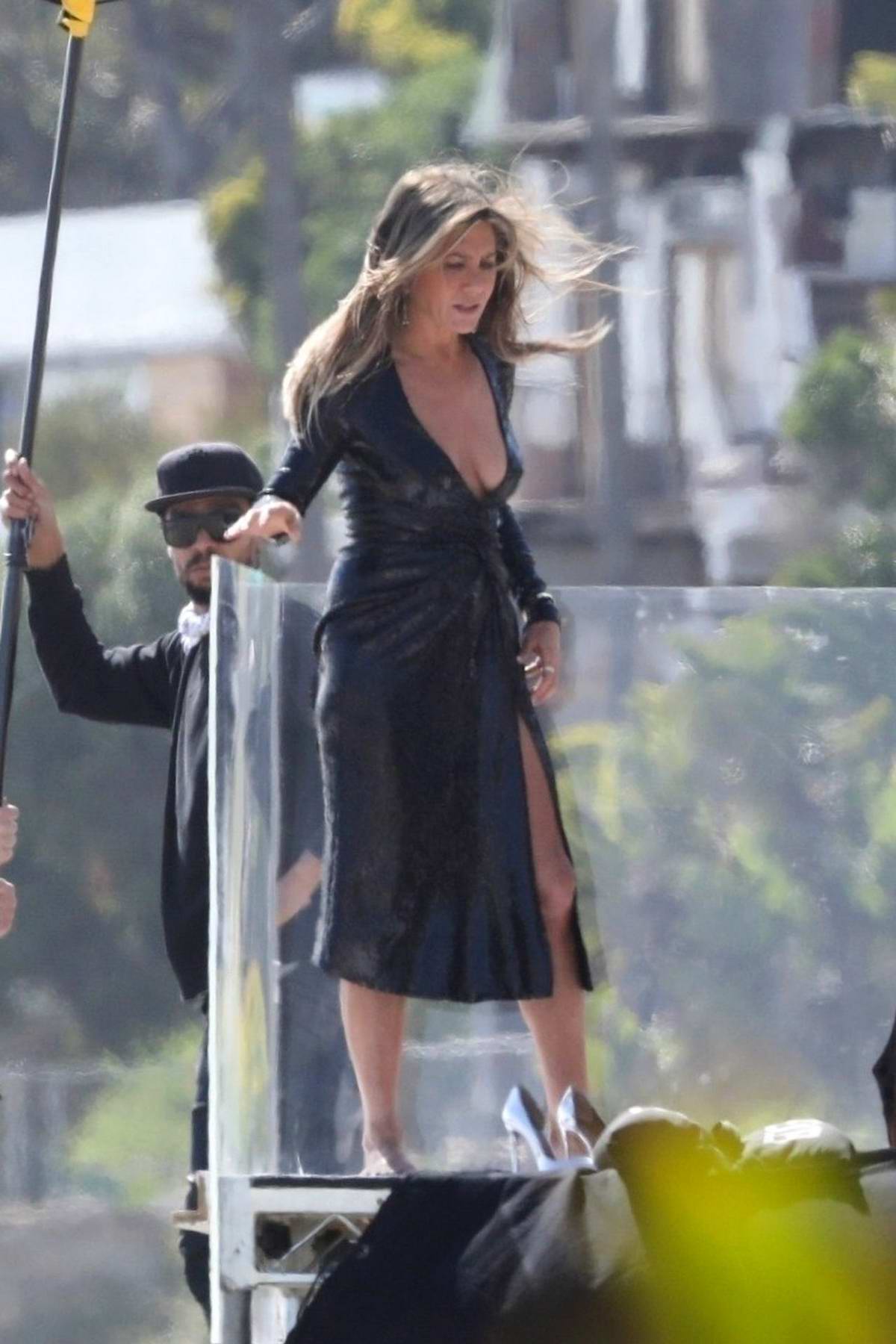 jennifer aniston poses in a plunging black dress with a dog during a