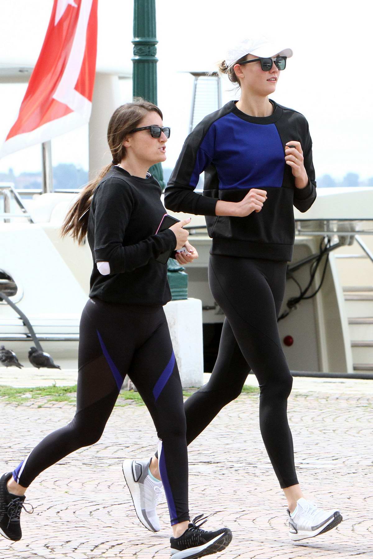 Karlie Kloss wears a blue and black sweatshirt with black leggings while  out for a run