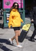 Emily Ratajkowski rocked a bright orange hoodie and black legging shorts as she heads out with her luggage in New York City