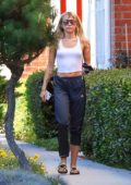 Miley Cyrus seen wearing a white tank top and Adidas track pants as she  leaves after