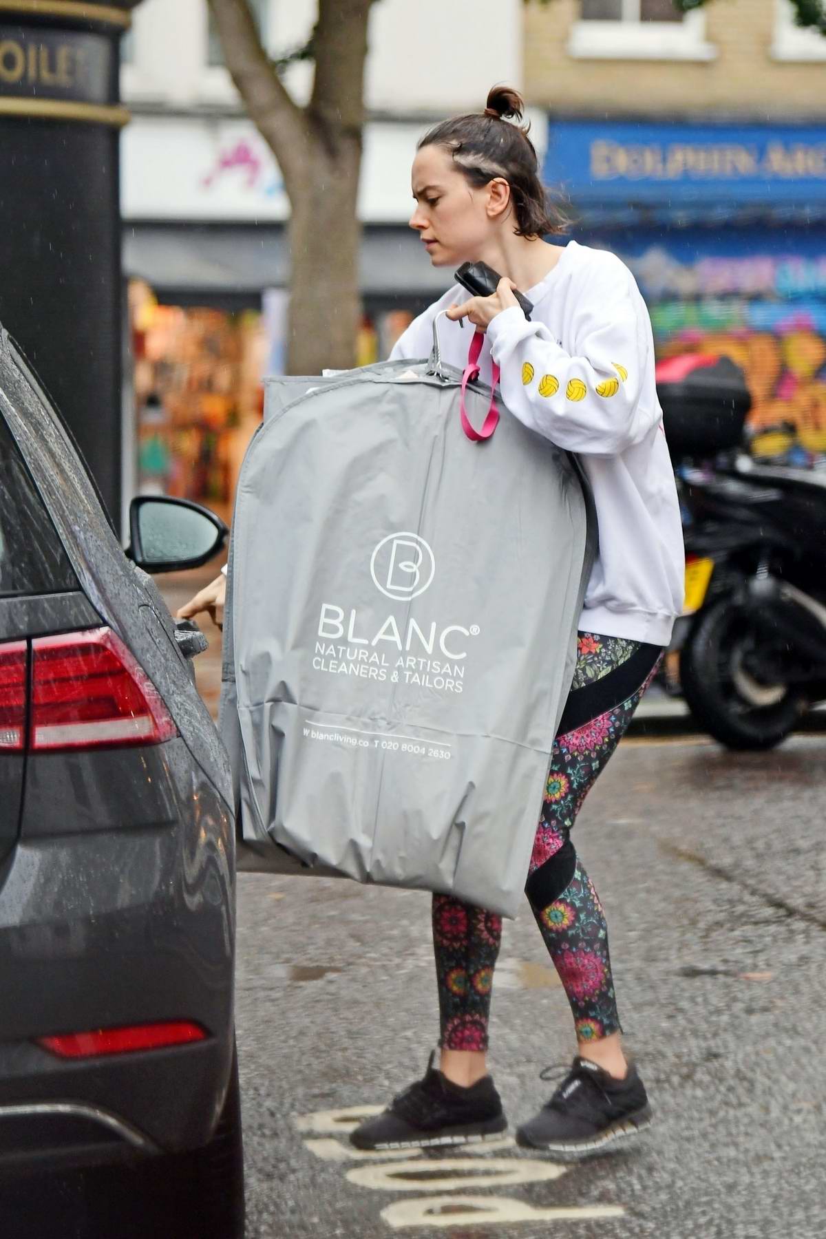 Daisy Ridley wears a white sweatshirt and colorful leggings while