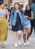 Sadie Sink wears a plaid dress, denim jacket and sneakers while out for a stroll with some friends in New York City