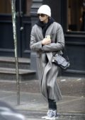 Kaia Gerber wears a grey long coat, scarf, and beanie as she steps out in New York City