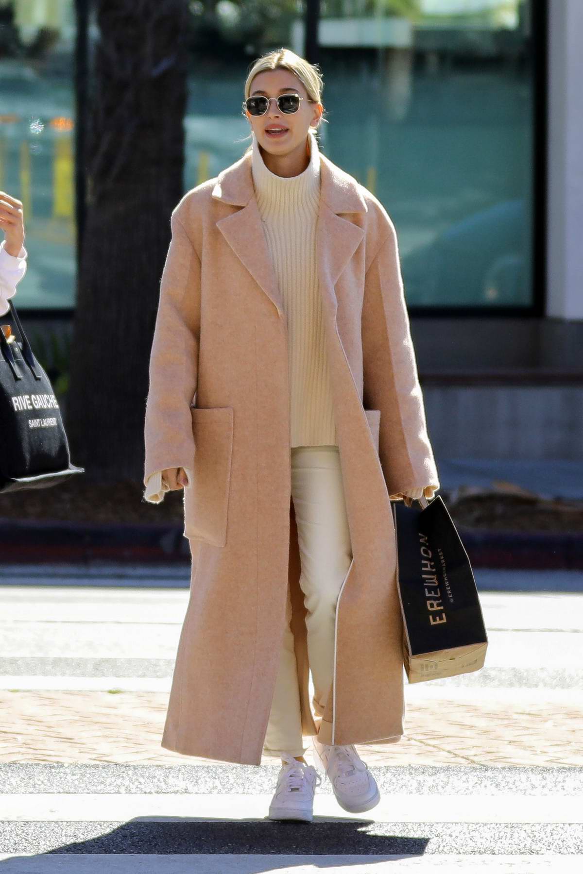 Hailey Bieber wears a beige long coat and Nike Air Force 1s as she steps out