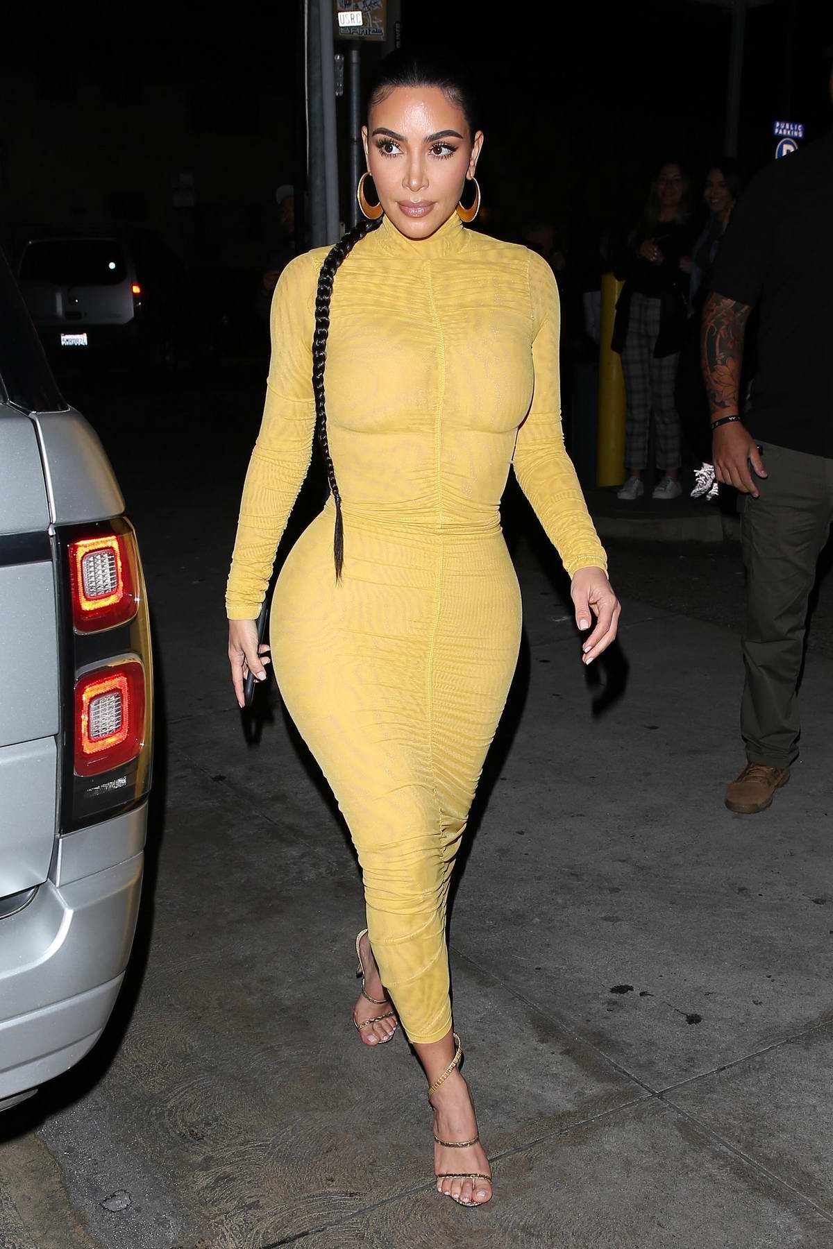 Kim Kardashian stuns in a form-fitting yellow dress as she arrives