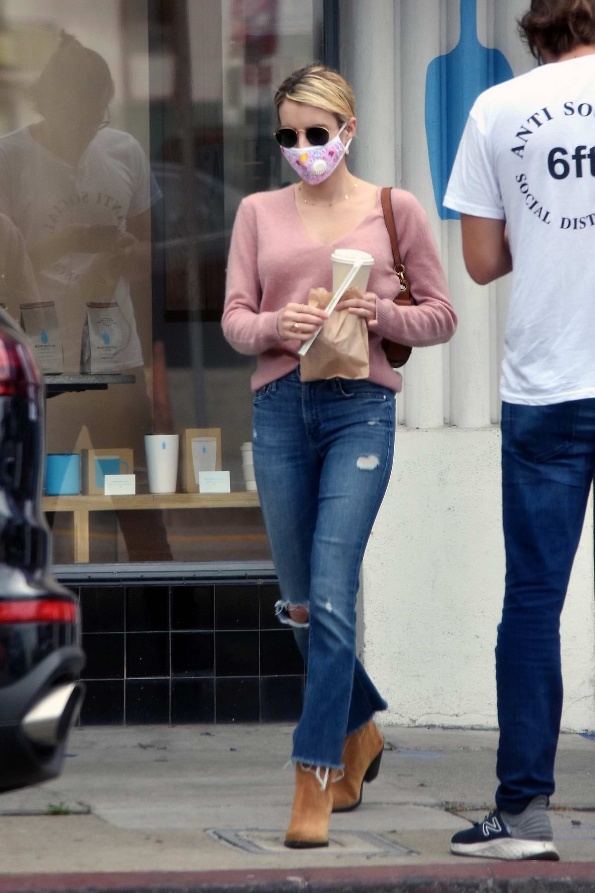 Emma Roberts looks trendy in a pink sweater, ripped jeans and suede boots  during a coffee