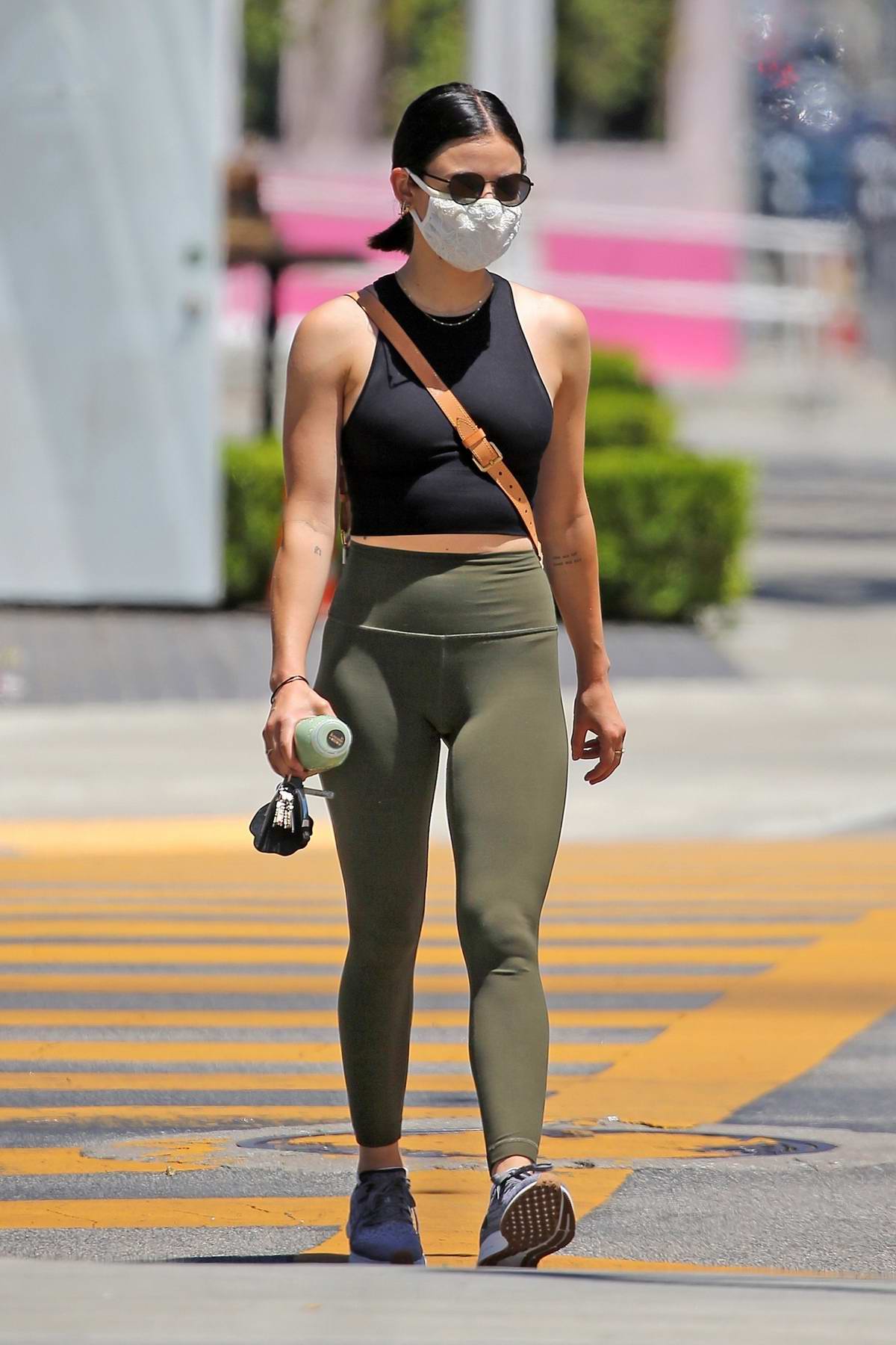 Lucy Hale rocks a crop top and olive green leggings during a juice