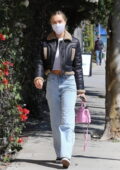 Alexis Ren looks good in a white crop top with a leather jacket and jeans while visiting P.volve studio in Los Angeles