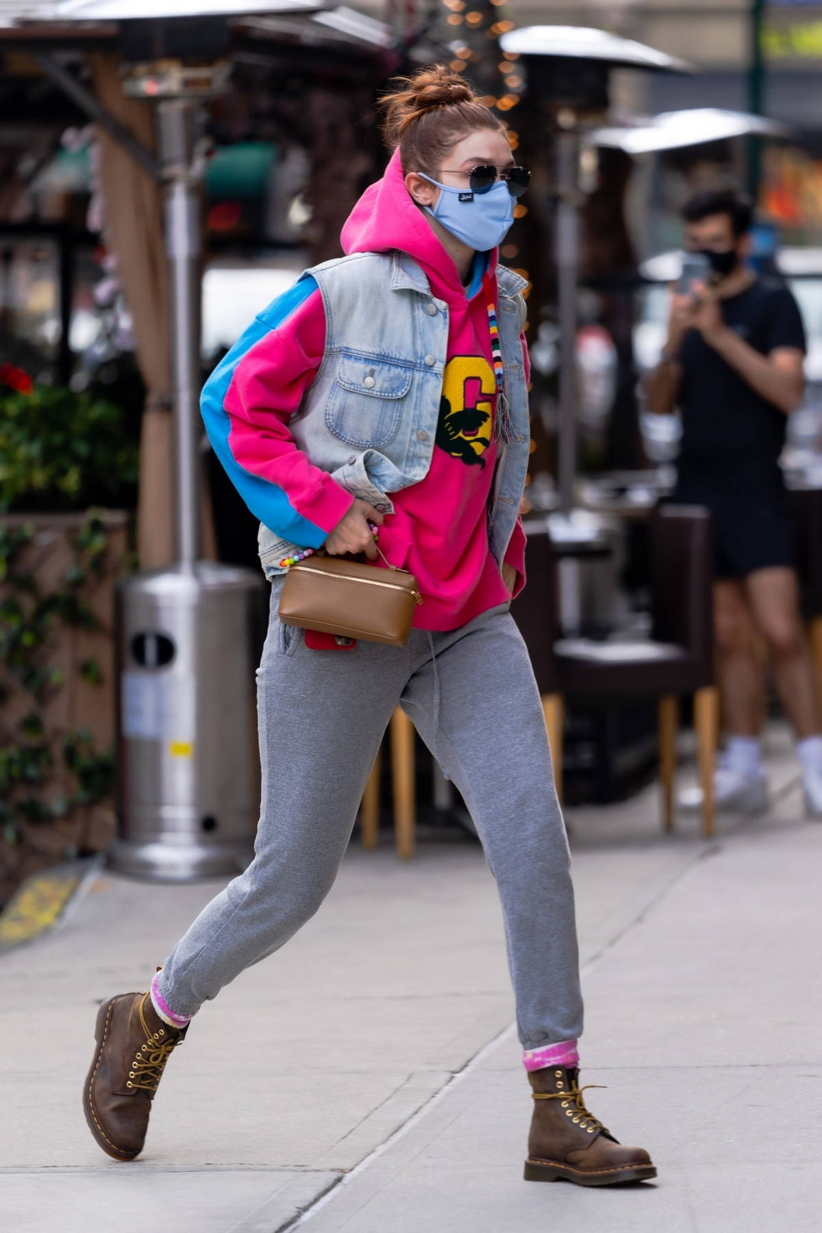 Gigi Hadid sports a pink and blue hoodie with a denim vest and grey  sweatpants for