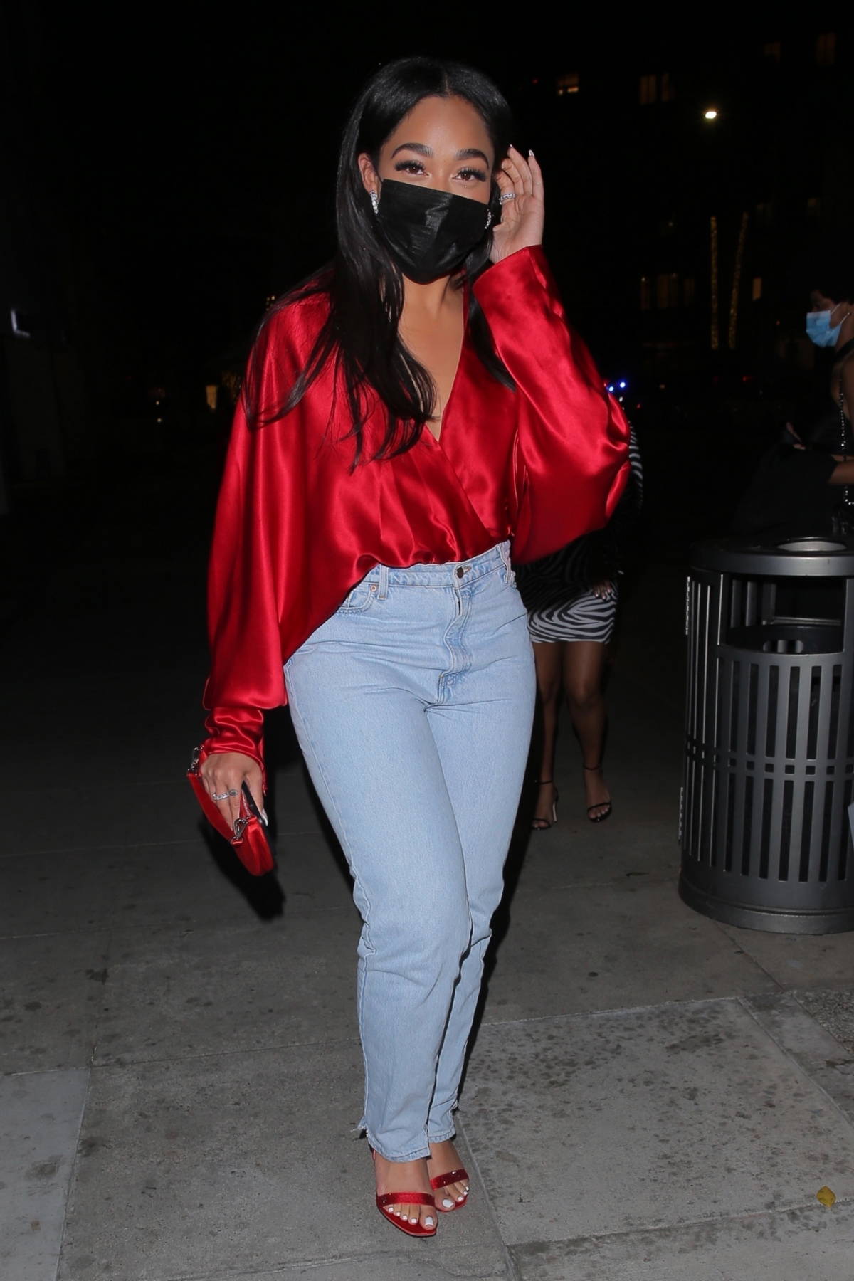 Jordyn Woods cuts a casual figure rocks a silk red top with jeans