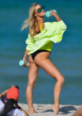 Joy Corrigan looks vivacious in a neon green swimsuit as she curls some weights during a photoshoot in Miami Beach, Florida