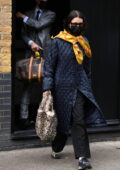 Bella Hadid looks chic in a black quilted coat and yellow scarf while leaving her hotel in London, UK