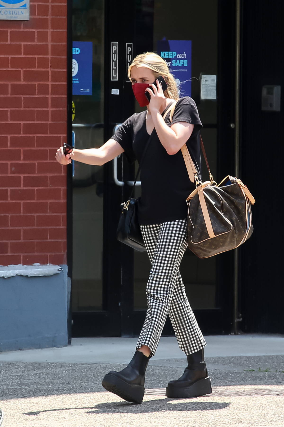 Emma Roberts wears checkered pants and black tee as she steps out carrying  a Louis Vuitton