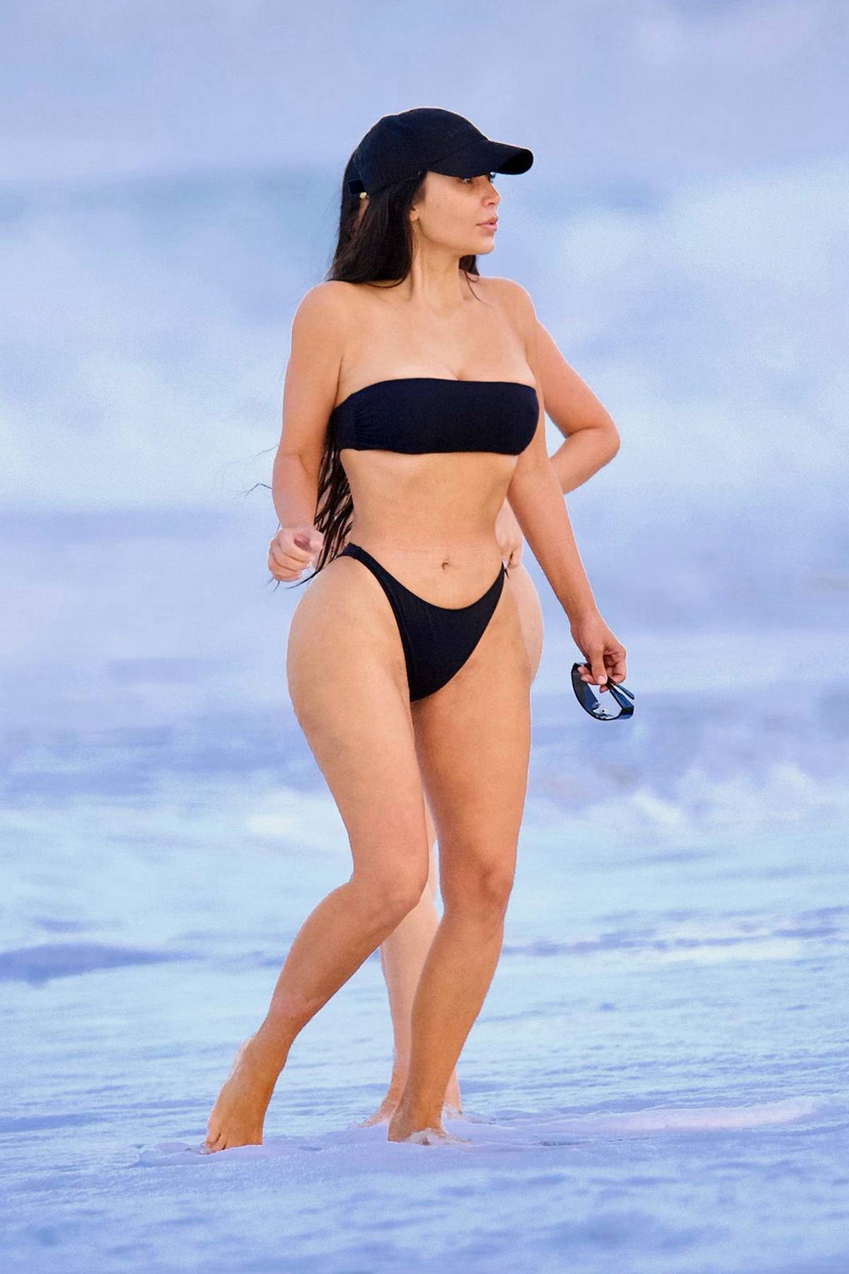 Kim Kardashian shows off her famous curves in a black bikini as she hits the  beach