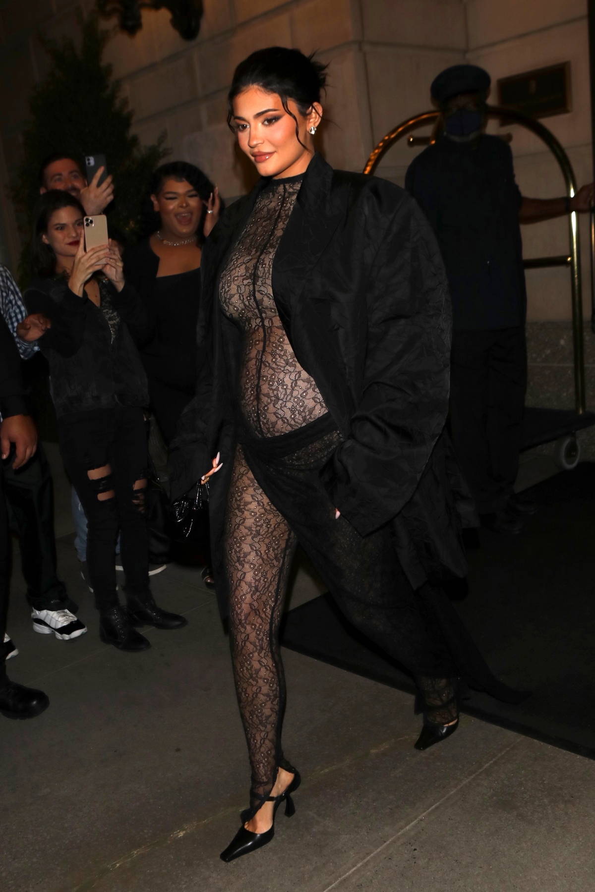 Kylie Jenner stuns in a sheer lace jumpsuit with a black duster while  attending a birthday