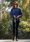 Kaia Gerber wears a blue sweatshirt and black leggings as she takes her dog out for a walk in Los Angeles