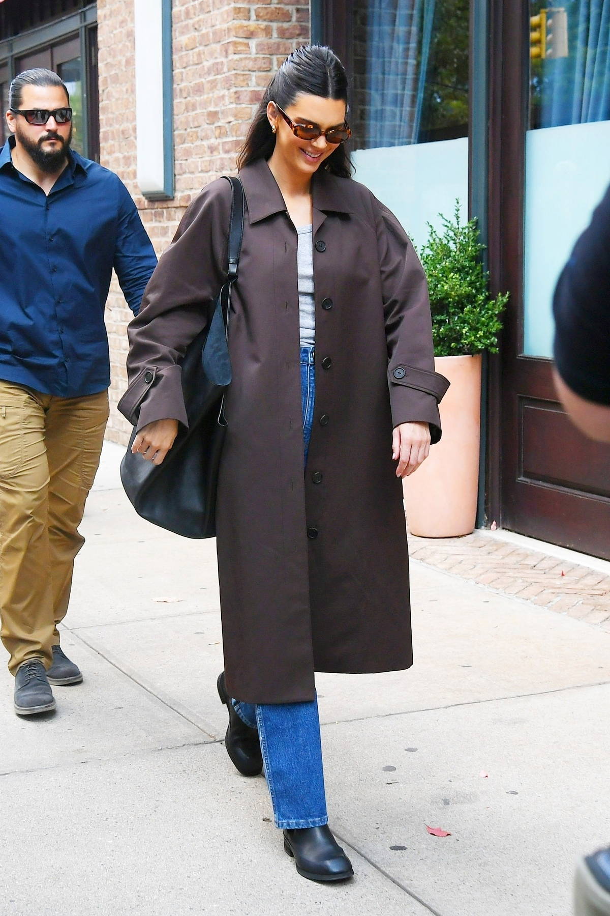 Kendall Jenner cuts a casual figure in a brown trench coat and blue ...