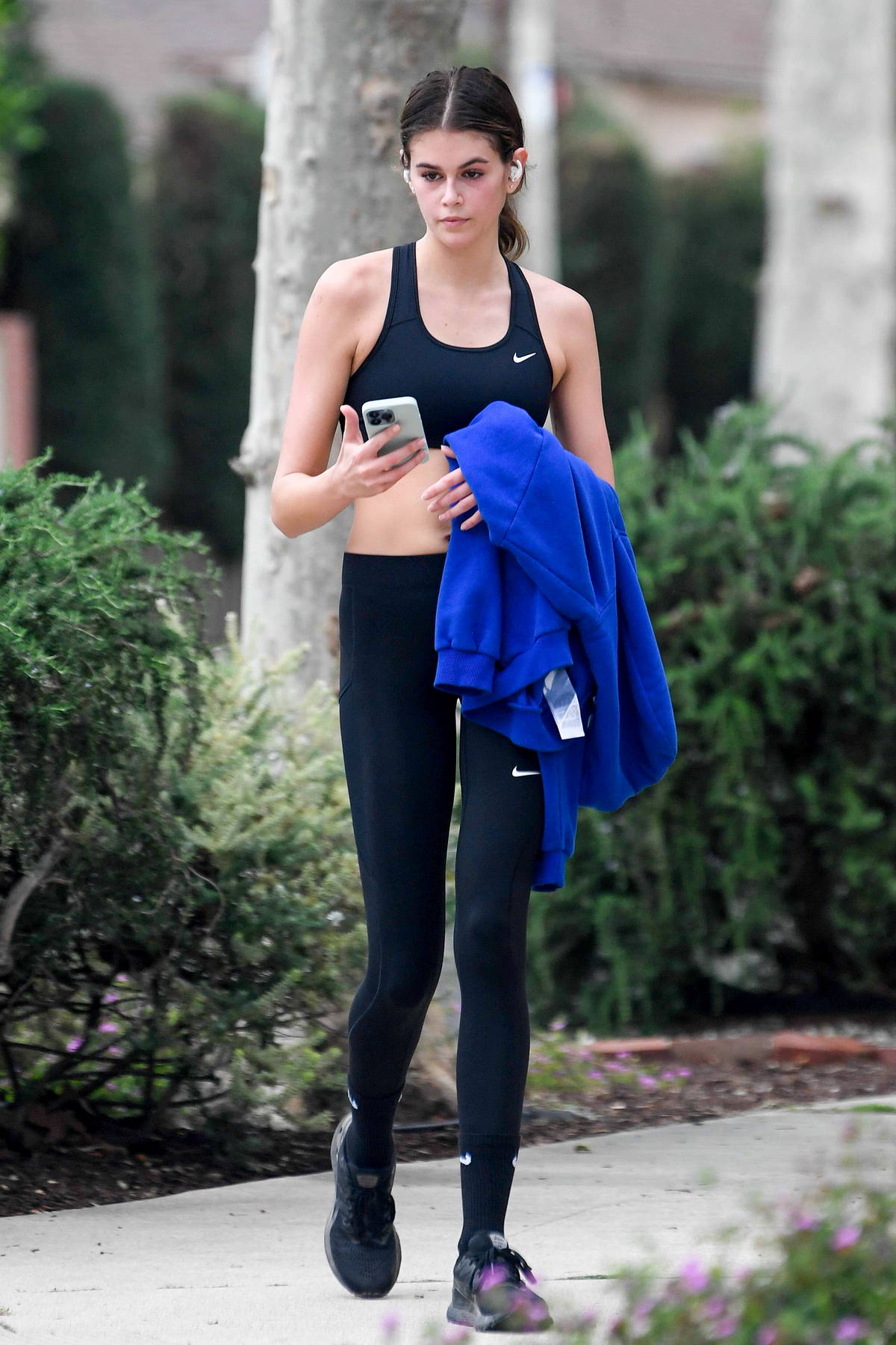 Kaia Gerber shows off her slender figure in a black sports bra and leggings  while leaving