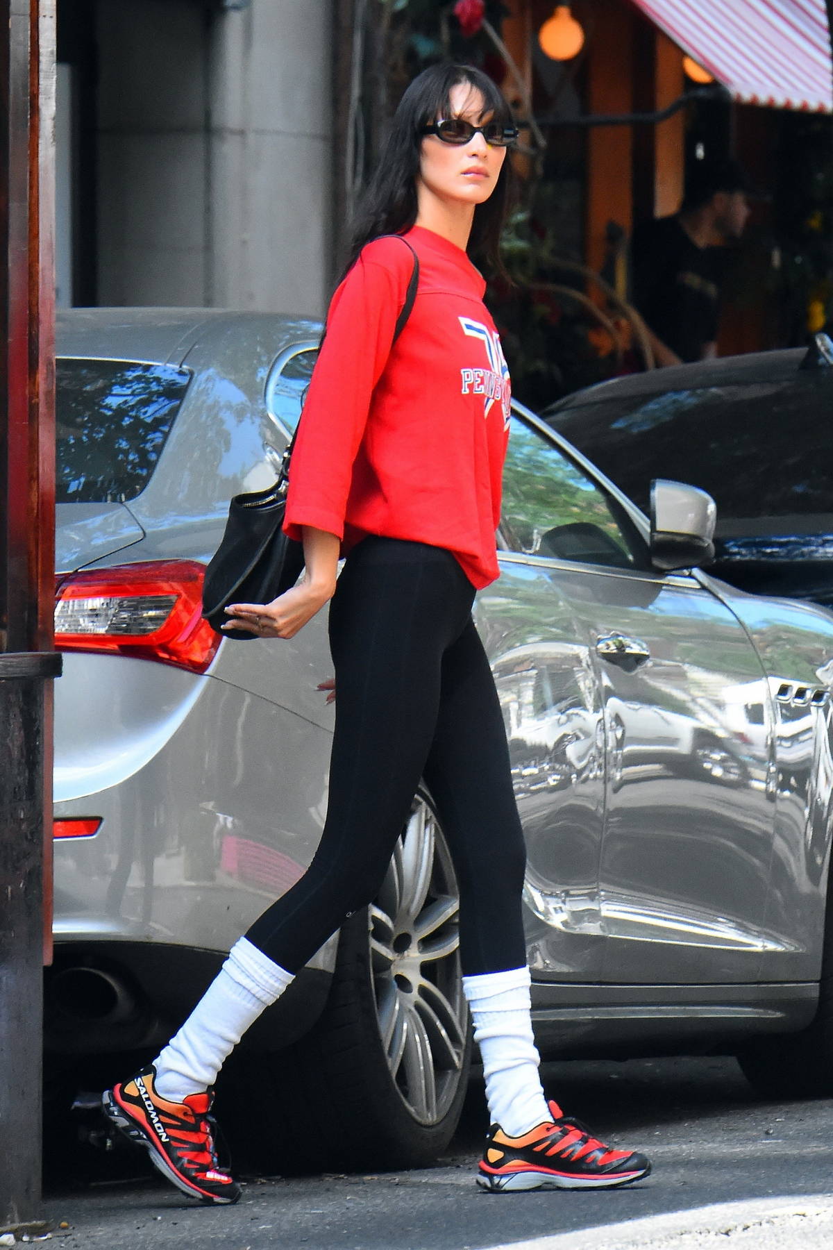 Bella Hadid wears a bright red sweater and black leggings while