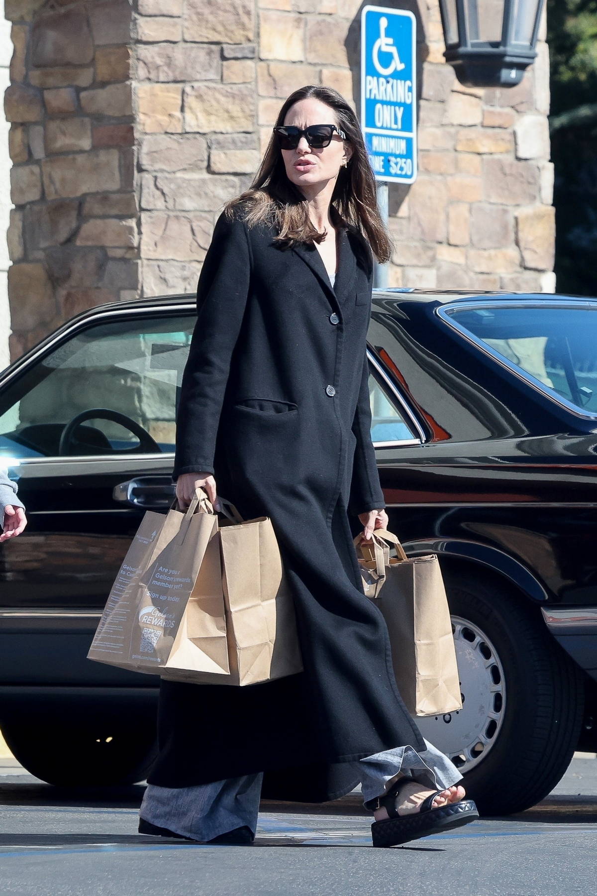 Angelina Jolie in long black coat with beige top handle bag in LA on  October 11 ~ I want her style - What celebrities wore and where to buy it.  Celebrity Style