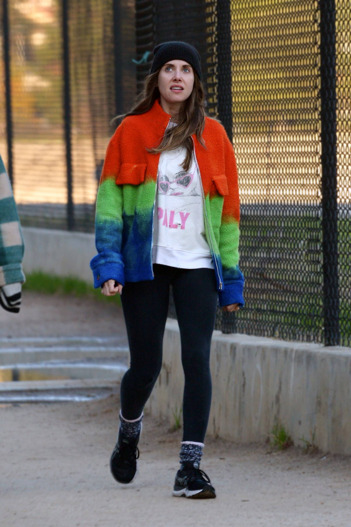 alison brie wears a colorful fleece and black leggings as she goes