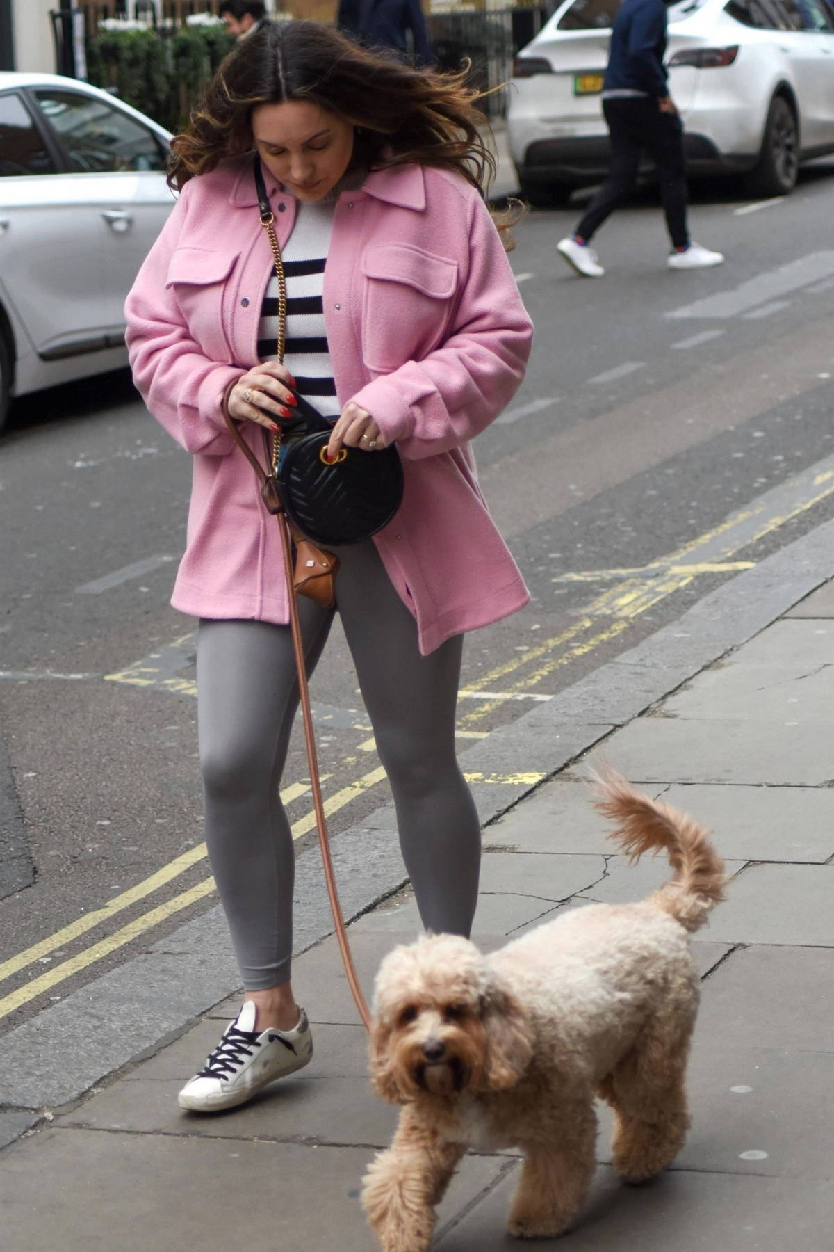 Kelly Brook wears a pink jacket and grey leggings while walking her dog around Soho in London, UK