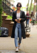 Emily Ratajkowski looks casual yet trendy in a leather trench coat paired with a white crop top during an outing in New York City