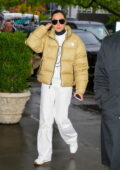 Gal Gadot wears a yellow North Face jacket with her all-white ensemble while arriving back to her hotel in New York City