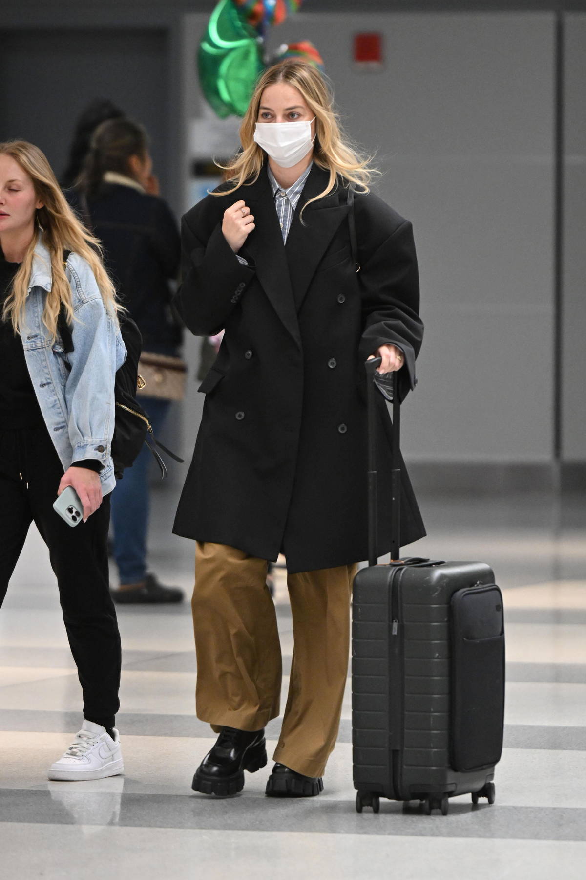 Margot Robbie looks great in a black coat and khaki trousers as