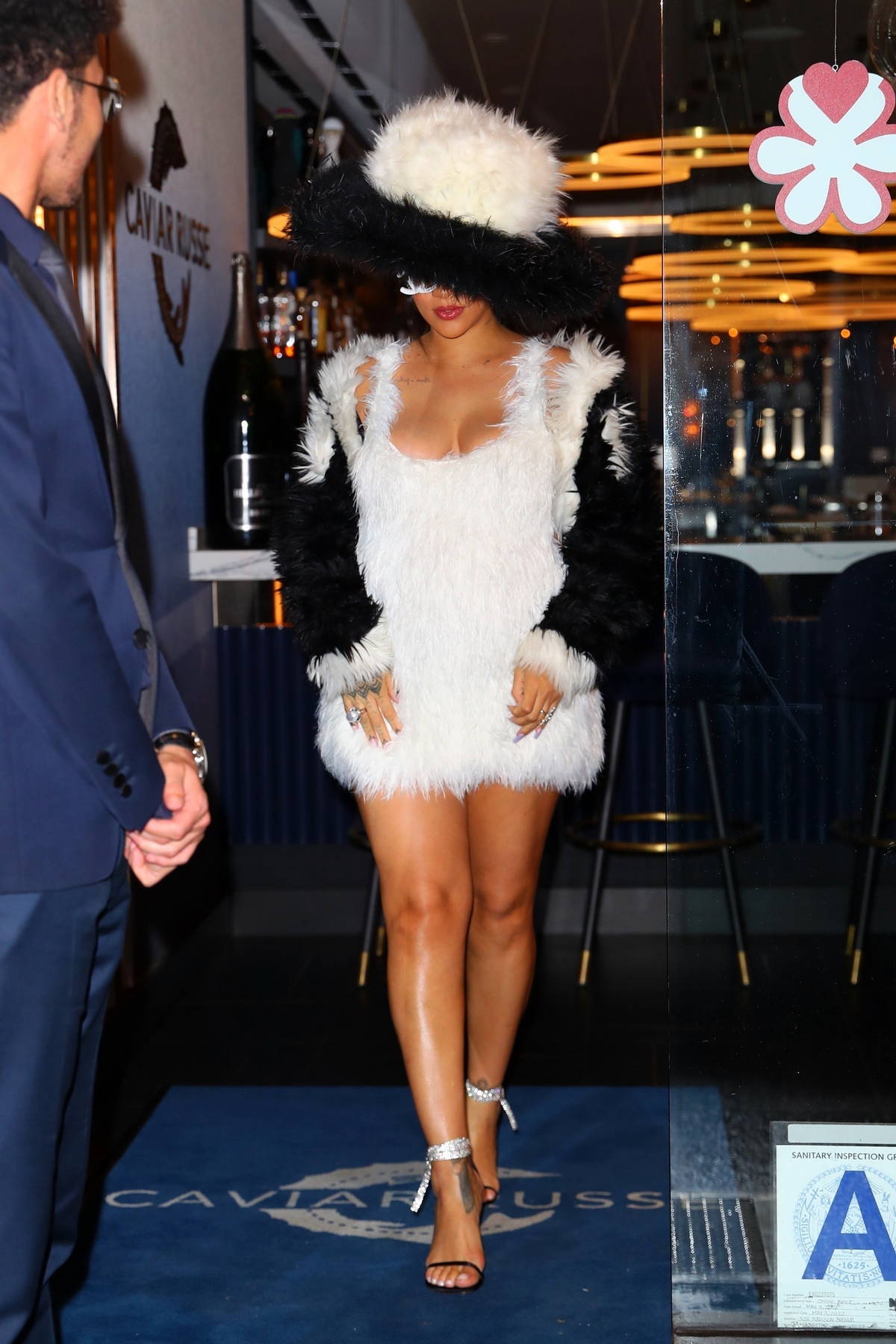 Rihanna Wears Brown Minidress, Louis Vuitton Bag, and Trucker Hat