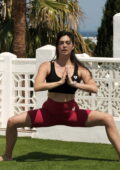 Casey Batchelor sports a black crop top and red bike shorts during her Yoga session in Ibiza, Spain