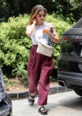 Lucy Hale wears a cropped white tank top and burgundy pants as she arrives at Edition Hotel in West Hollywood, California
