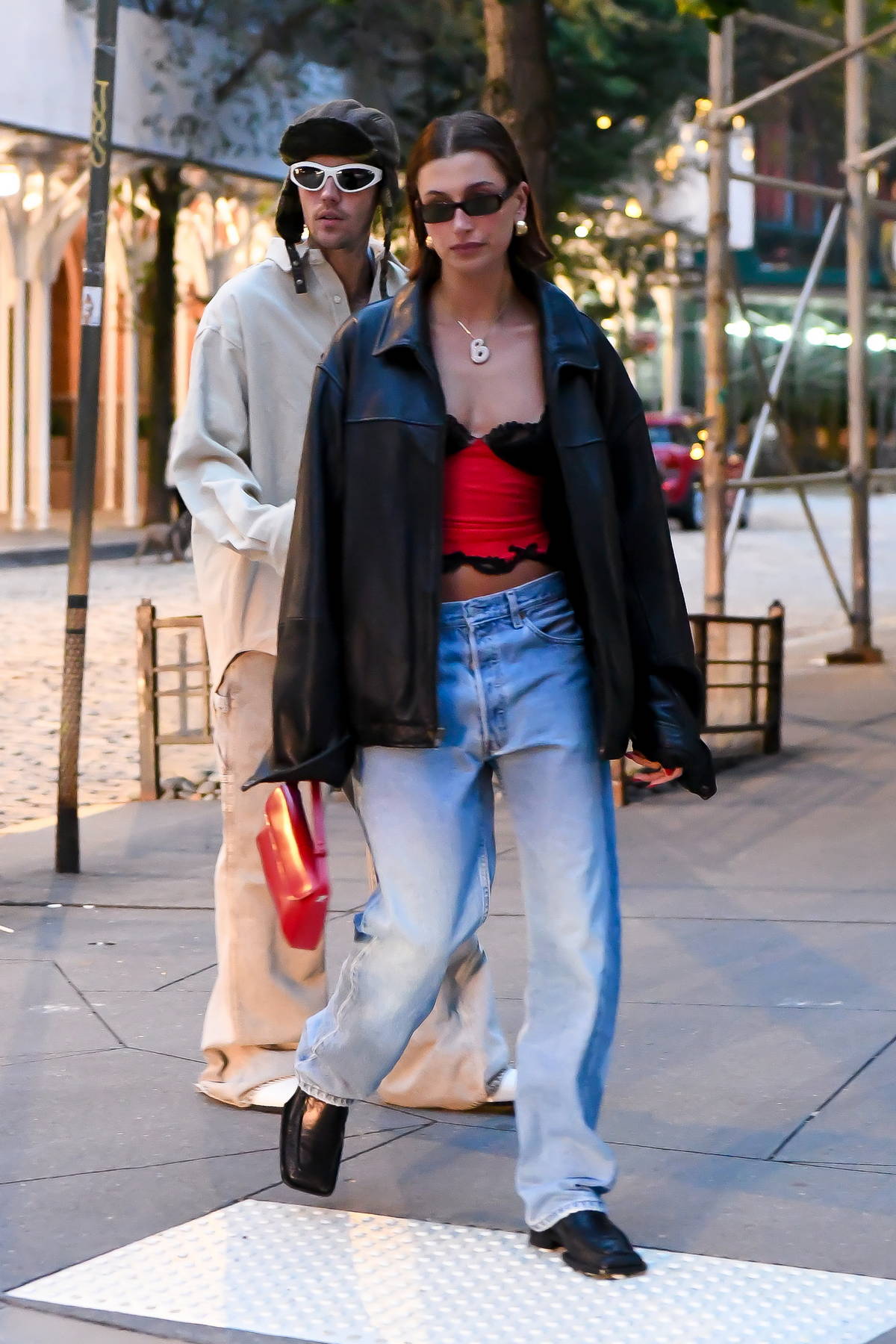Hailey Bieber wears a leather jacket over a red crop top and baggy ...