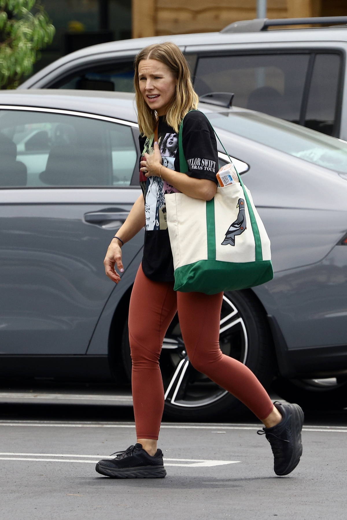 https://www.celebsfirst.com/wp-content/uploads/2023/08/Kristen-Bell-wears-a-Taylor-Swift-t-shirt-and-burnt-orange-leggings-while-shopping-groceries-with-her-daughter-in-Los-Angeles-090823_3.jpg