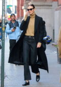 Karlie Kloss looks stylish in a black trench coat with a beige turtleneck sweater and jeans while heading out in New York City