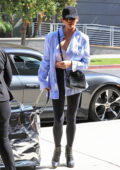 Chrissy Teigen dons a sports bra underneath an unbuttoned shirt paired with black leggings while stepping out in Beverly Hills, California