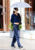 Kaia Gerber flashes glimpse of her toned abs in a navy sweater while running errands on a rainy day in New York City