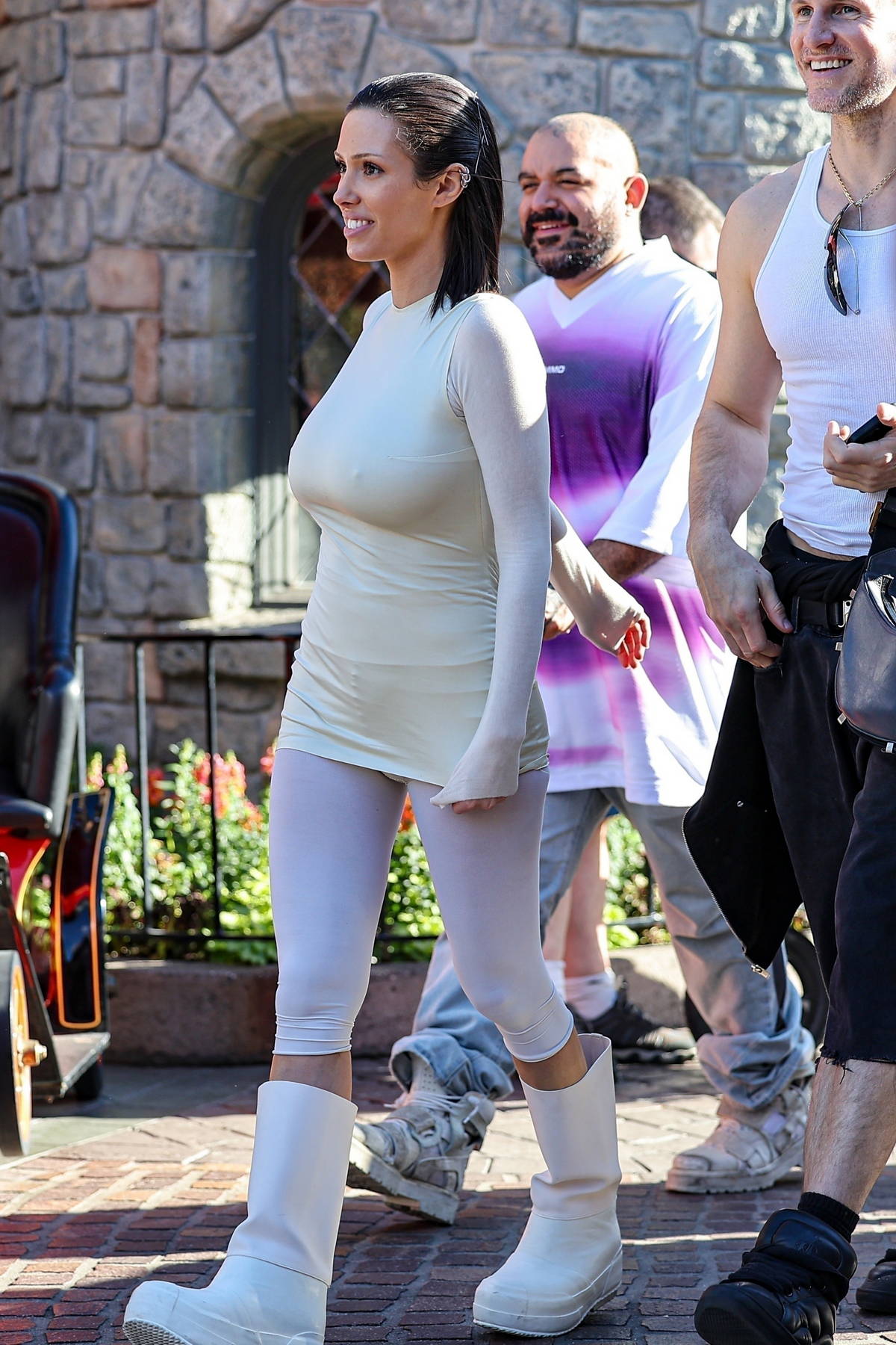 Bianca Censori dons a form-fitting outfit with white leggings and boots as she enjoys a day with friends at Disneyland in Anaheim, California