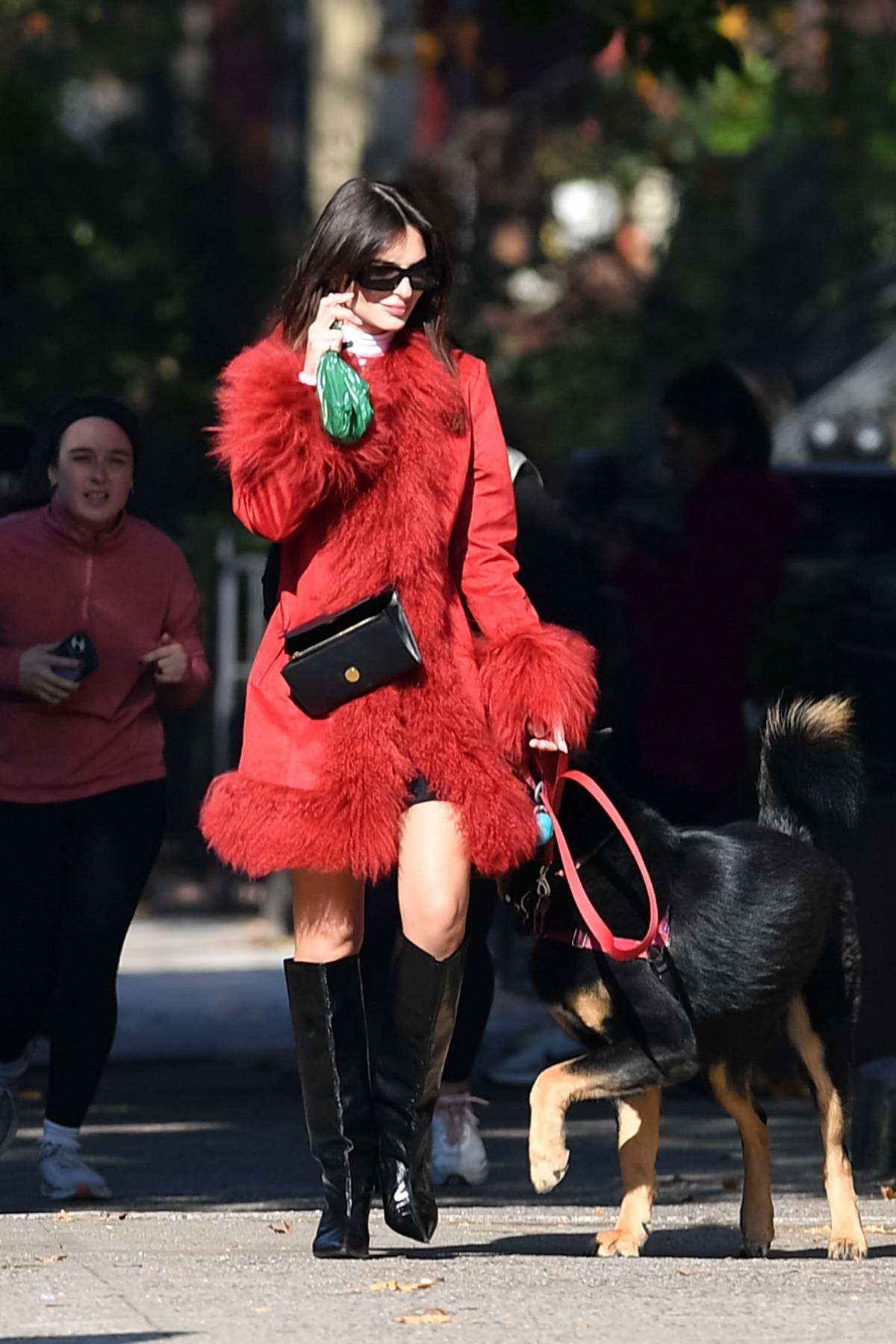 Emily Ratajkowski Looks stylish in a red fur-trimmed coat and knee high boots while out on a dog walk in New York City